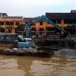Dredging operation: a digger on two floaters, prevented from floating away by a boat